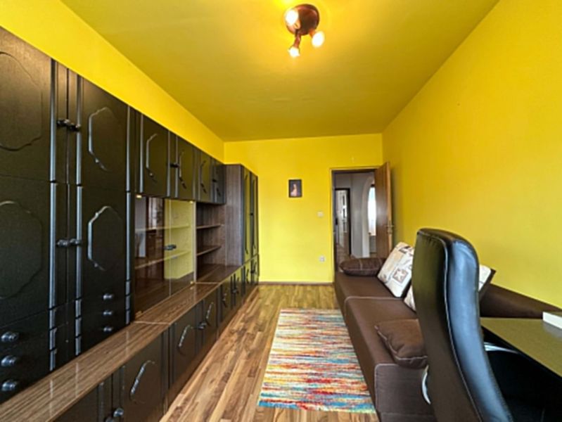 Na predaj kompletne zariadený 3 izbový byt s klimatizáciou aj s balkón - Žlté steny obývačky v 3-izbovom byte s tmavým nábytkom a dreveným dekorom.