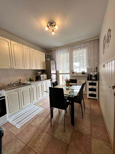 Na predaj kompletne zariadený 3 izbový byt s klimatizáciou aj s balkón - Kuchyňa v 3-izbovom byte s bielymi skrinkami, jedálenským stolom a dlažbou.