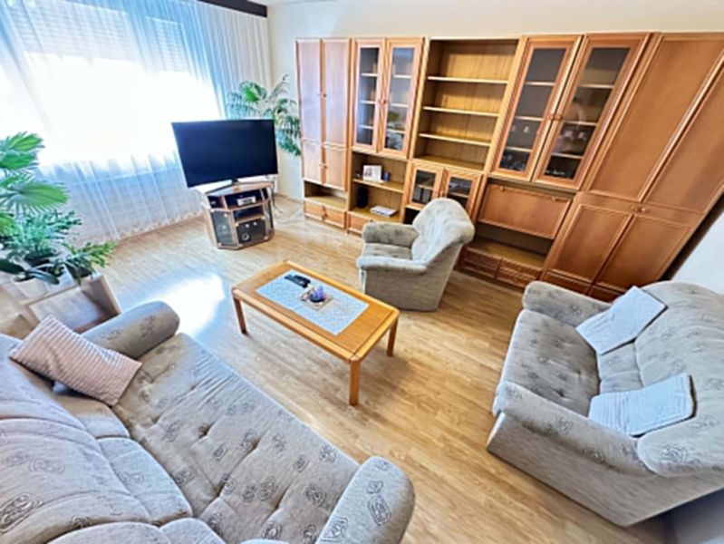 Na predaj kompletne zariadený 3 izbový byt s klimatizáciou aj s balkón - Obývačka v 3-izbovom byte ponúka útulný nábytok a podlahu s dreveným dekorom.