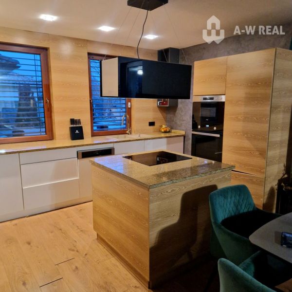 Znížená cena    Luxusný 4-izbový rodinný dom s letnou kuchyňou a nádhe - Kuchyňa v rodinnom dome s podlahou s dreveným dekorom a moderným zariadením.