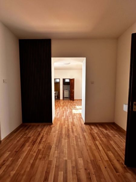 Na predaj 2-izb. byt v dvojdome (110 m²) v štandarde s krbom – Možnosť - Chodba v rodinnom dome s podlahou s dreveným dekorom a svetlými stenami.