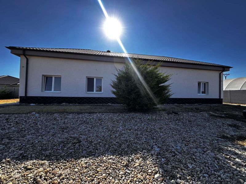 Na predaj 2-izb. byt v dvojdome (110 m²) v štandarde s krbom – Možnosť - Rodinný dom v Zemianskej Olči so slnkom na oblohe a kamenistým dvorom.
