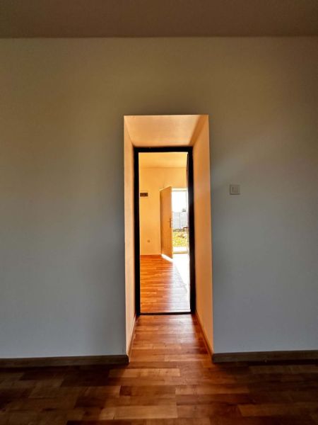 Na predaj 2-izb. byt v dvojdome (110 m²) v štandarde s krbom – Možnosť - Interiér rodinného domu so stenou v svetlej farbe a podlahou s dreveným dekorom.