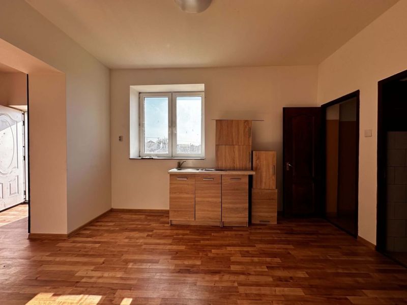 Na predaj 2-izb. byt v dvojdome (110 m²) v štandarde s krbom – Možnosť - Interiér rodinného domu s podlahou s dreveným dekorom a kuchynskou linkou.