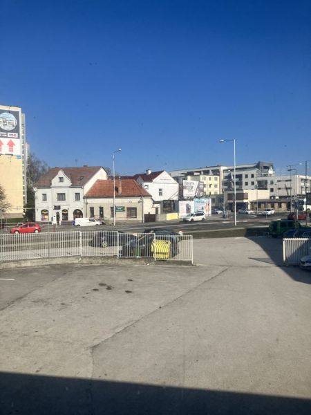 Prenájom skladový priestor v centre mesta + vlastné parkovanie - Ulica s budovami a autami, Dunajská Streda, blízko skladov a hál.