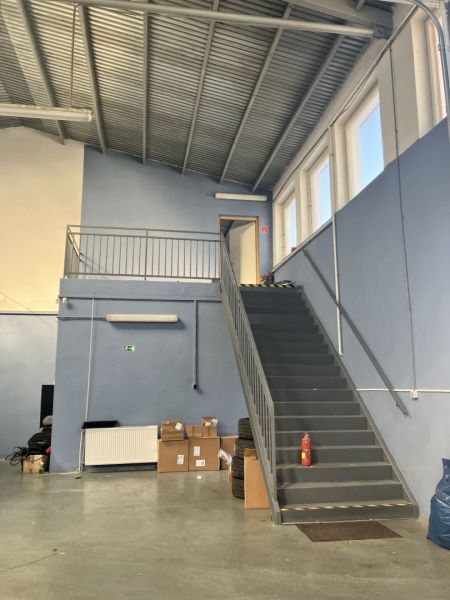 Prenájom skladový priestor v centre mesta + vlastné parkovanie - Sklady a haly s kovovým schodiskom, krabicami a pneumatikami na podlahe.