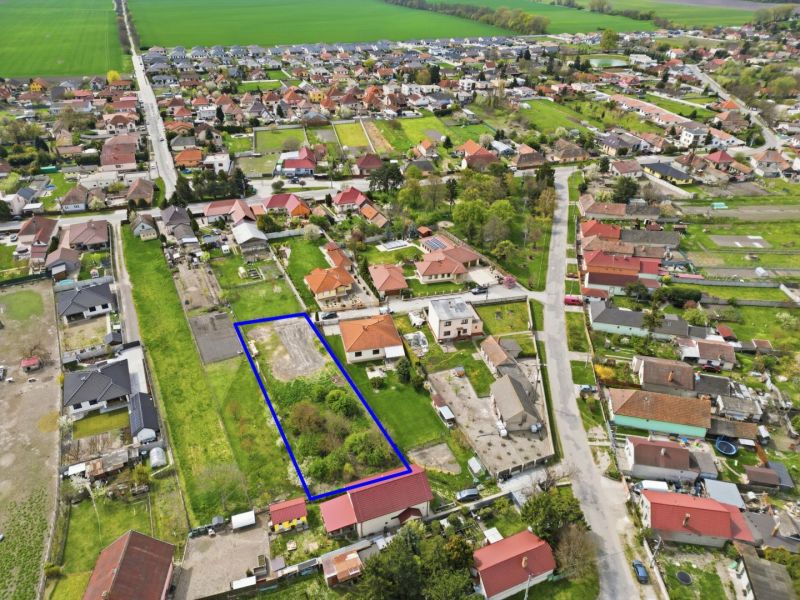 Na predaj stavebný pozemok v obci Horná Potôň - Letecký pohľad na pozemok vhodný na bývanie v Hornej Potôni, obklopený domami a záhradami.
