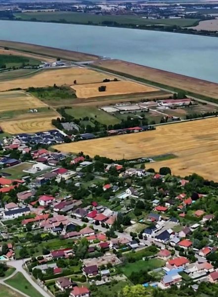 NOVÁ CENA! PREDAJ SLNEČNÝ POZEMOK V BLÍZKOM OKOLÍ BRATISLAVY - Letecký pohľad na Dobrohošť a polia pozdĺž Dunaja v oblasti ulic Dobrohošť. Pozemky - bývanie.