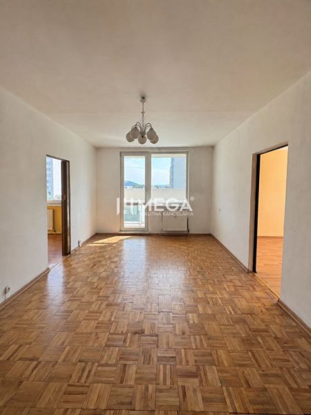 Na predaj 3 izbový byt s balkónom na Sidl.III v Humennom - Izba v 3-izbovom byte s podlahou s dreveným dekorom a závesným svietidlom.