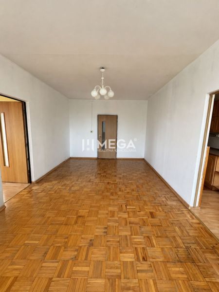 Na predaj 3 izbový byt s balkónom na Sidl.III v Humennom - Obývacia izba v 3-izbovom byte s podlahou s dreveným dekorom a lustrom.