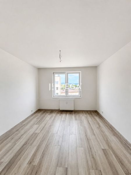 Na predaj  – 2 izbový byt s balkónom v Strážskom - Svetlý prázdny priestor s bielymi stenami a podlahou s dreveným dekorom v 2-izbovom byte.