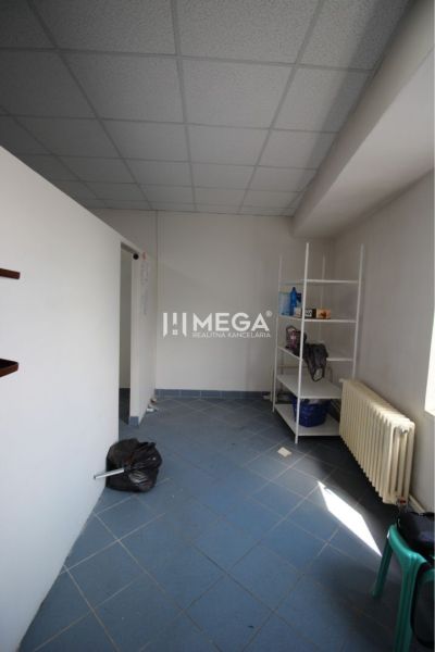 Na prenájom - priestor 185 m2 v centre mesta Humenné - Interiér obchodných priestorov s modrou podlahou, regálom a radiátorom.