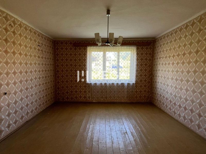 Na PREDAJ - Dom s krásnym pozemkom v Zbudskej Belej - Izba s tapetami a podlahou s dreveným dekorom v rodinnom dome.