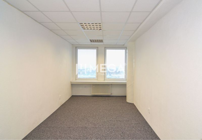 NA PRENÁJOM POSLEDNÉ VOĽNÉ kancelárie v centre mesta – 17,5 m² - Interiér kancelárie s bielymi stenami, kobercom a dvoma oknami.