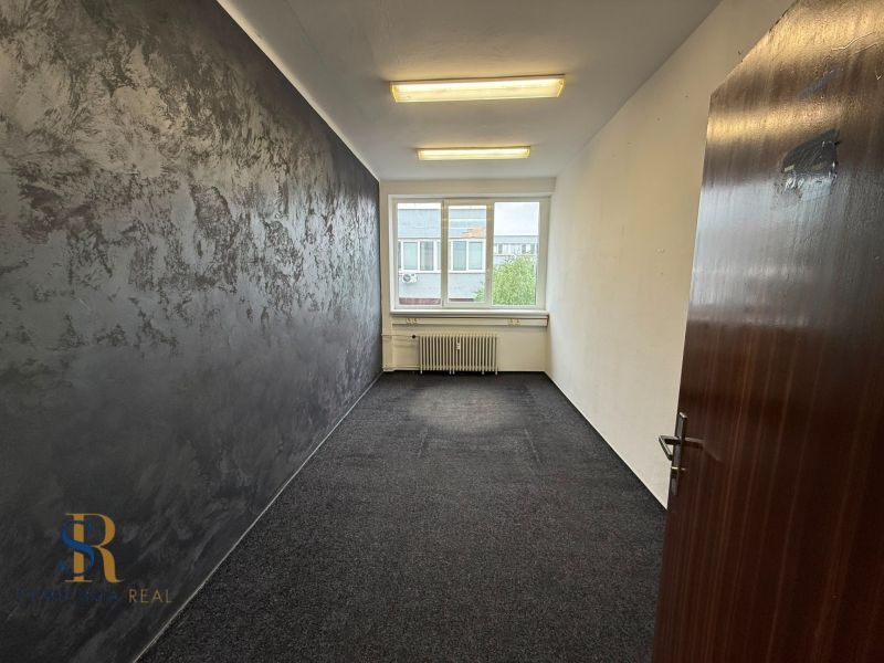 Prenájom obchodných priestorov v centre Galanty - Kancelária s tmavosivou stenou, kobercom a veľkým oknom.