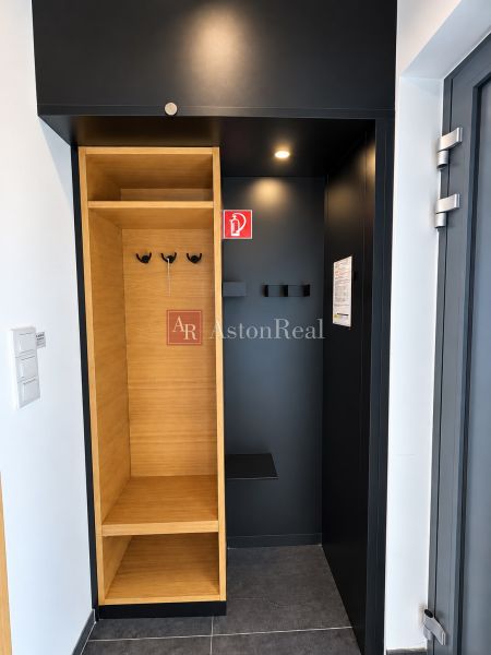 Predaj! INVESTUJTE DO MIESTA, KAM SA ĽUDIA VRACAJÚ – TATRALANDIA - Vstupná časť rodinného domu s dreveným dekorom, úložným priestorom a tmavými stenami.