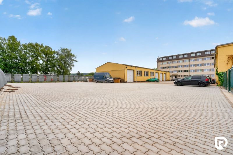 Prenájom 37m2 kancelárie | ul. Brnianska | Trenčín - Parkovisko a žltá budova na Brnianskej ulici v Trenčíne, vhodné pre kancelárie.