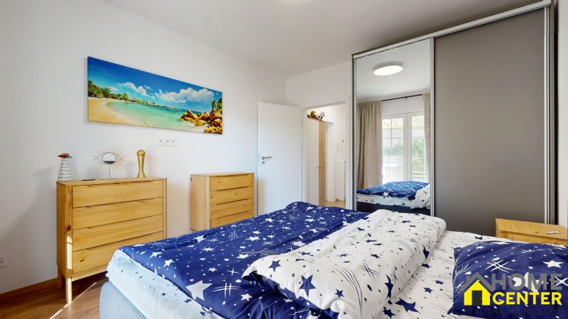 PRENÁJOM 2 izbový, zariadený byt v Danube residencia - REZERVOVANÉ - Spálňa v 2-izbovom byte s podlahou s dreveným dekorom, bielymi stenami a obrazom pláže.