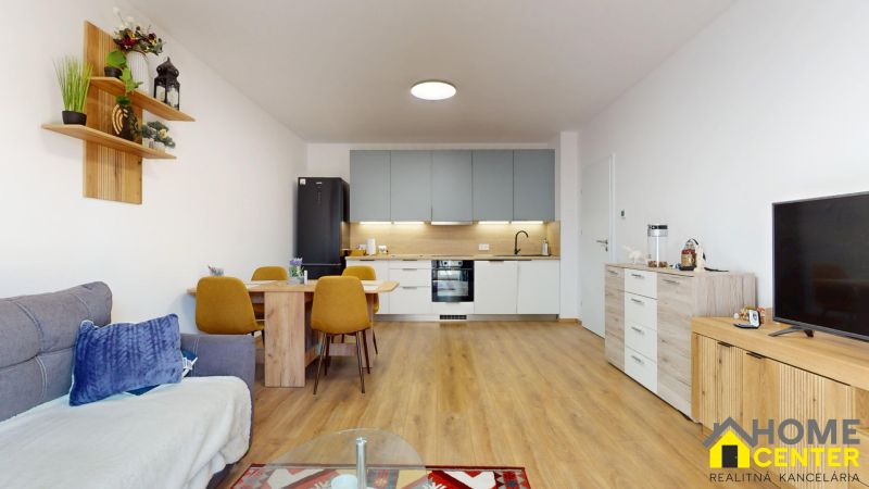 PRENÁJOM 2 izbový, zariadený byt v Danube residencia - REZERVOVANÉ - Obývačka s kuchyňou v 2-izbovom byte s podlahou s dreveným dekorom a jedálenským stolom.