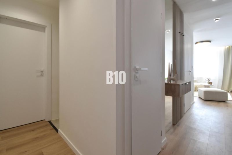 Rezervované-BÔRIK - 4-izbový BYT S GARÁŽOU - Interiér 4-izbového bytu s podlahou s dreveným dekorom a minimalistickým nábytkom.