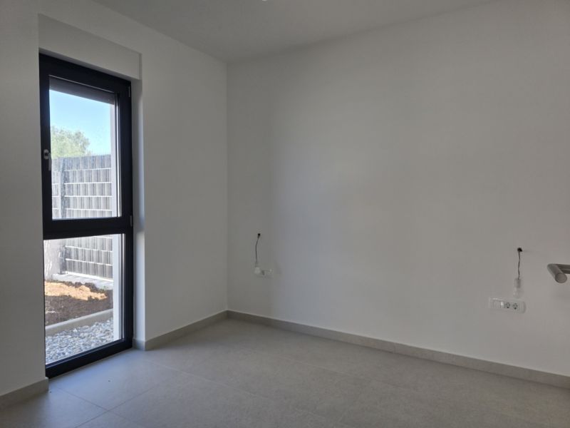 CHORVÁTSKO - Apartmán so záhradou 270 m2 - PRIVLAKA - Prázdna miestnosť s veľkým oknom vo 4-izbovom byte, podlaha s dlaždicami.