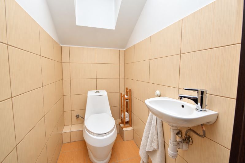 Predaj 4i dom, 52 m2 garáž, 518 m2 pozemok, Mosonmagyaróvár - Kúpeľňa v rodinnom dome s toaletou a umývadlom, béžové kachličky.