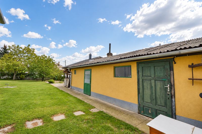Predaj 4i dom, 52 m2 garáž, 518 m2 pozemok, Mosonmagyaróvár - Záhrada rodinného domu v Mosonmagyaróvári s trávnikom a stromami.