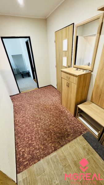 Na predaj 3 i byt 73 m2 s loggiou Partizánske – balkón, komora, špajza - Chodba s nábytkom a kobercom v 3-izbovom byte s podlahou s dreveným dekorom.