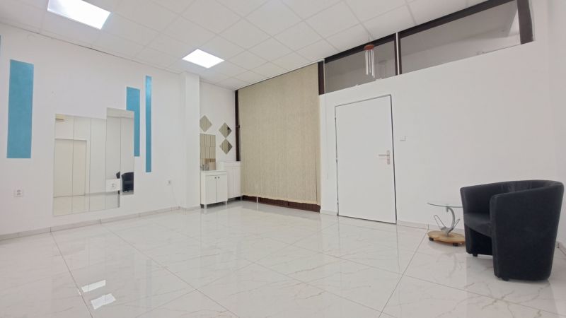 Priestor pre vaše podnikanie na prenájom v Šali – Veča - Interiér obchodných priestorov s kreslom, zrkadlami a dlažbou s bielym vzorom.