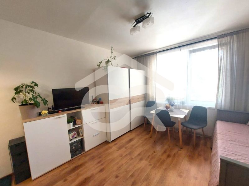 KOMPLETNE PREROBENÁ GARSÓNKA + PIVNICA: Nitra – Chrenová !  - Garsónka s podlahou s dreveným dekorom, skriňou, stolom a televíziou.