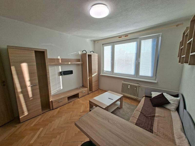DOBRÉ REALITY-pekná garsónka na prenájom, sídl. Kopanice, Prievidza - Garsónka so svetlým nábytkom, pohovkou a podlahou s dreveným dekorom.
