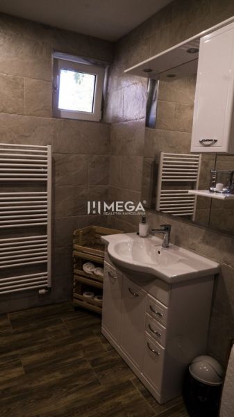 Na predaj nehnuteľnosť - zabehnutý penzión v centre mesta Humenné - Kúpeľňa s umývadlom, skrinkou, rebríkovým radiátorom a podlahou s dreveným dekorom.