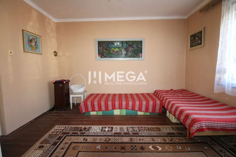 NA PREDAJ - Dom v obci Volica - Izba v rodinnom dome s kobercami, posteľami a stojacou kachľou.