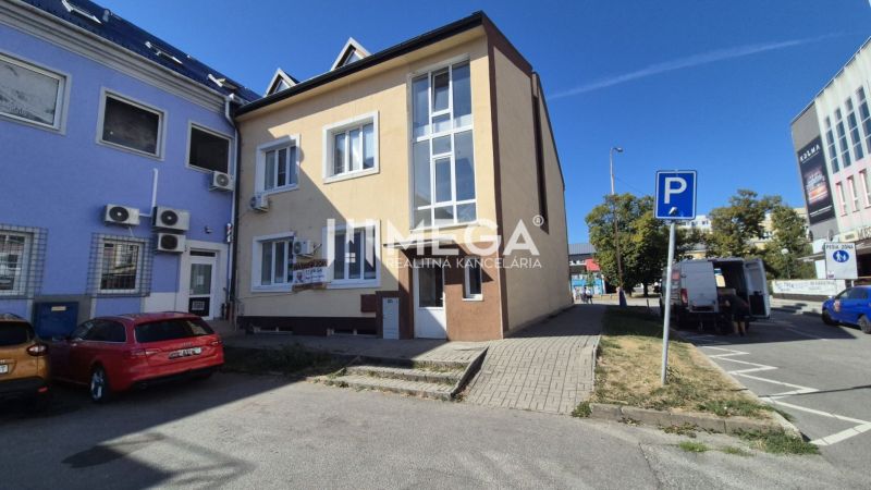 PRENÁJOM OBCHODNÉHO PRIESTORU PRIAMO V CENTRE HUMENNÉHO - Budova s obchodnými priestormi na Námestí Slobody v Humennom, pred ktorou sú parkovacie miesta.