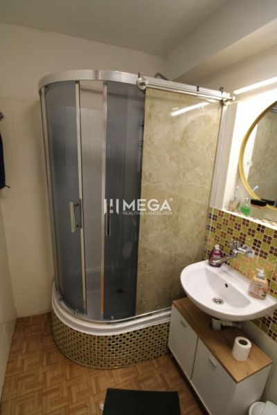REZERVOVANÝ - Na predaj moderný 2-izbový byt po rekonštrukcii - Kúpeľňa v 2-izbovom byte s podlahou s dreveným dekorom, sprchovým kútom a umývadlom.
