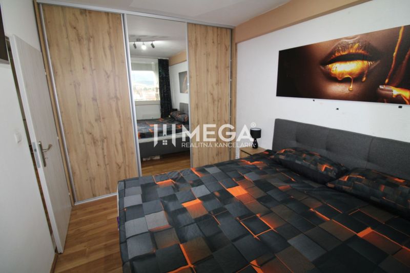 REZERVOVANÝ - Na predaj moderný 2-izbový byt po rekonštrukcii - Spálňa s posteľou a skriňou s posuvnými dverami, podlaha s dreveným dekorom.