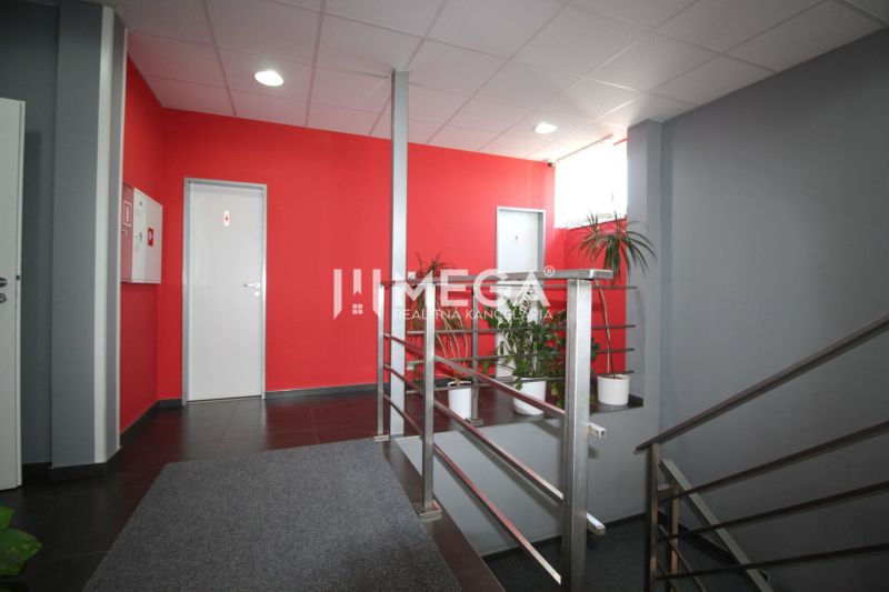 NA PRENÁJOM: 2x Moderná, klimatizovaná kancelária s parkovaním a optic - Kancelárie s červenou stenou a šedými podlahami, rastliny a kovové zábradlie.