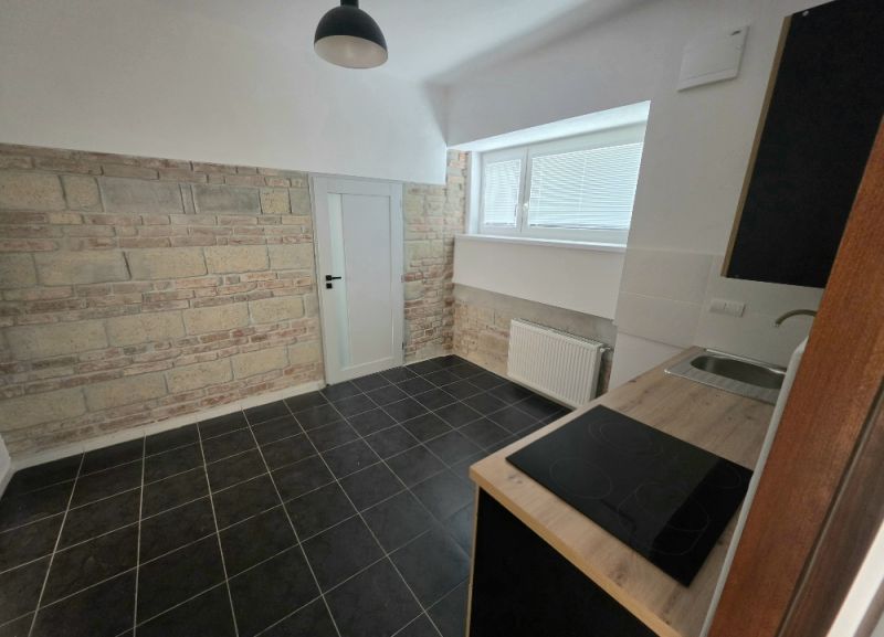 PRENÁJOM Bánovce nad Bebravou/2 IZBOVÝ BYT/CENTRUM-STRED/70m2 - Kuchyňa v 2-izbovom byte s obkladom z tehál a čiernou dlažbou.