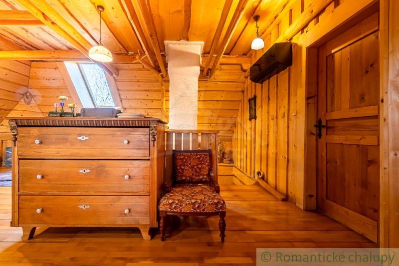 Požitavský dvor pri Topoľčiankach - Drevenica s dušou a obrovským pote - Podkrovie rodinného domu so skriňou, kreslom a podlahou s dreveným dekorom.