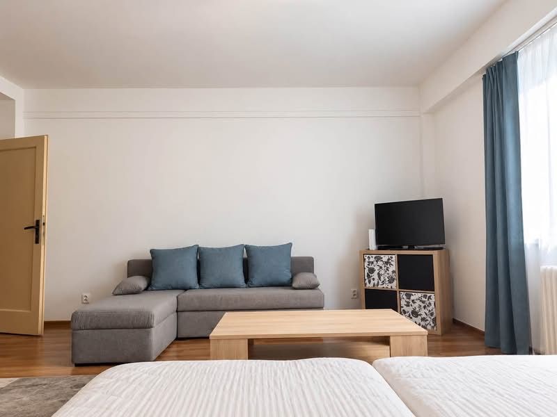 Prenájom 1-izbového zariadeného bytu, 43 m² – Šancová - Štýlový obývací priestor v 1-izbovom byte s pohovkou a TV, podlaha s dreveným dekorom.