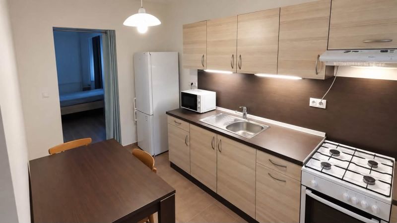 Prenájom 1-izbového zariadeného bytu, 43 m² – Šancová - Kuchyňa v 1-izbovom byte s dreveným dekorom, sporákom a jedálenským stolom.