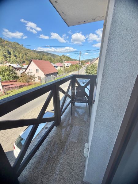 Prenájom 1 izbového bytu v centre obce Oščadnica - Balkón s výhľadom na ulicu Centrum v Oščadnici obklopený zeleňou a domami, 1-izbový byt.