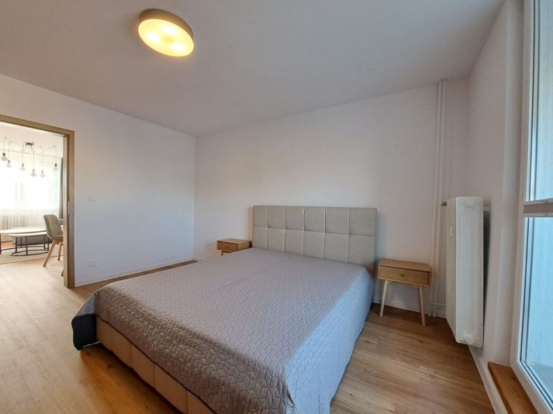 Prenájom kompletne zrekonštruovaného 2-izbového bytu s balkónom - Spálňa s posteľou a nočnými stolíkmi, podlaha s dreveným dekorom v 2-izbovom byte.