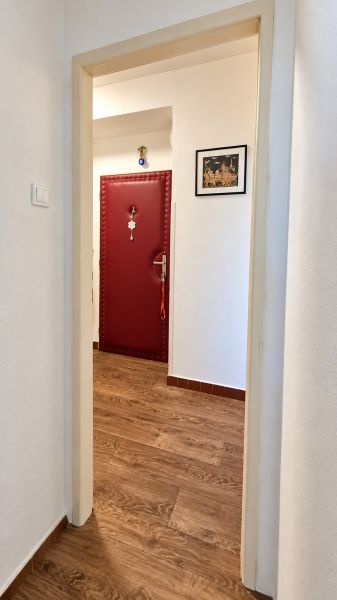 3-izbový byt v centre Pezinka, balkón, výťah, pivnica, komora - Chodba s červenými dverami a podlahou s dreveným dekorom v 3-izbovom byte.