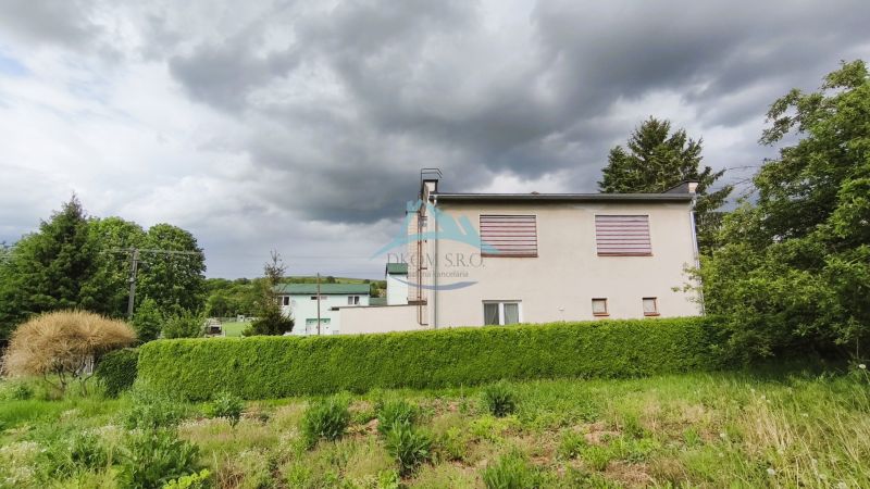 MIMORIADNE ZNÍŽENÁ CENA! Priestranný 6-izbový RD, Nenince, V. Krtíš. - Rodinný dom v Neninciach obklopený hustou zeleňou a stromami pod zamračenou oblohou.