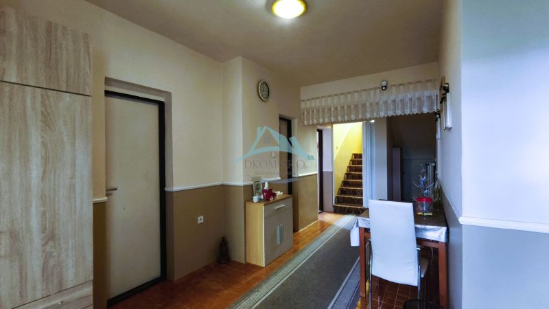 MIMORIADNE ZNÍŽENÁ CENA! Priestranný 6-izbový RD, Nenince, V. Krtíš. - Chodba v rodinnom dome s kobercovým schodiskom, stolom a podlahou s dreveným dekorom.