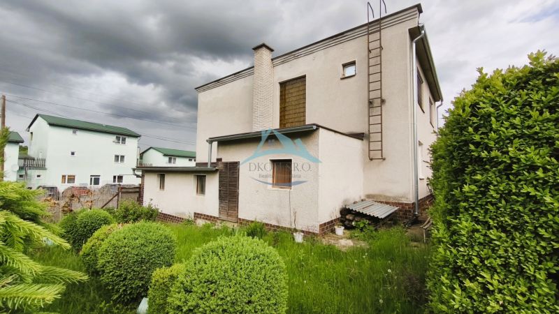 MIMORIADNE ZNÍŽENÁ CENA! Priestranný 6-izbový RD, Nenince, V. Krtíš. - Rodinný dom v Neninciach s trávnikom a kríkmi, pod zamračenou oblohou.