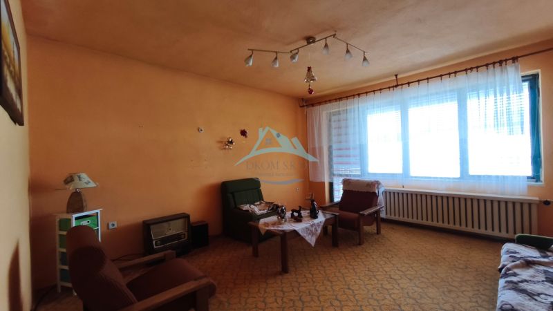 MIMORIADNE ZNÍŽENÁ CENA! Priestranný 6-izbový RD, Nenince, V. Krtíš. - Obývacia izba v rodinnom dome s oranžovými stenami a vintage nábytkom.