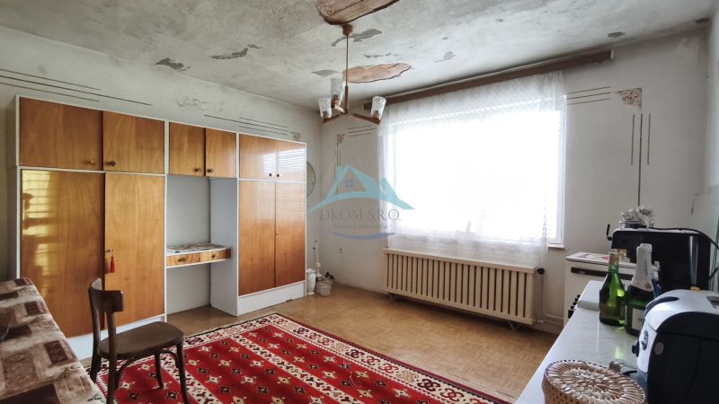 MIMORIADNE ZNÍŽENÁ CENA! Priestranný 6-izbový RD, Nenince, V. Krtíš. - Interiér rodinného domu s retro nábytkom, červeným kobercom a veľkým oknom.
