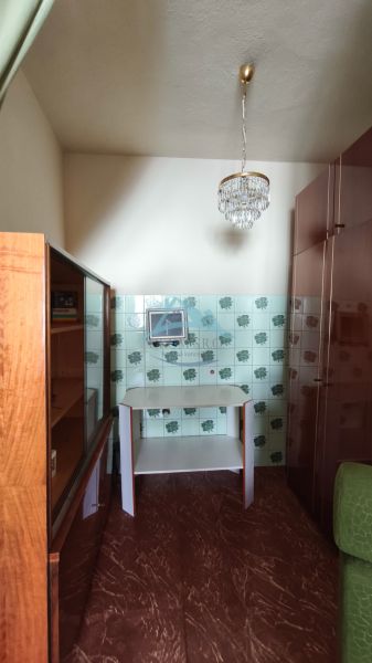 MIMORIADNE ZNÍŽENÁ CENA! Priestranný 6-izbový RD, Nenince, V. Krtíš. - Izba s lustrom, skrinkou a obkladmi so vzorom v rodinnom dome.